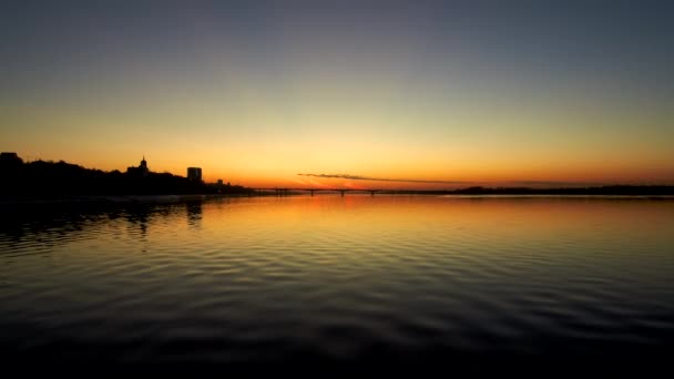 日没時に広い川を渡る橋の暗い空中写真、夕日が水に反射されます。 — ストック動画