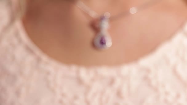 Schmuck. Ein silberner Anhänger mit einem magentafarbenen Diamanten am Hals der hübschen Mädchen. Geringe Schärfentiefe — Stockvideo