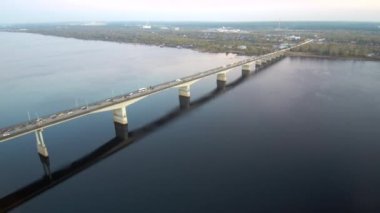 Geniş bir nehir üzerinde uzun bir köprünün havadan görünümü, köprüüzerinde aktif trafik.köprü suya yansır.4k.Kopya alanı