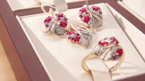 Brincos de ouro com diamantes em forma de coração magenta na joalheria. Close-up. Profundidade de campo rasa — Vídeo de Stock