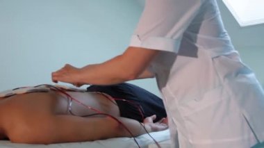Bir refleksolojist elektrostimülasyon için geri hastalarda elektrotlar düzeltir