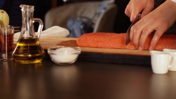 De chef-kok snijdt een groot stukje rauwe zalmfilet. Eiwitrijk voedsel — Stockvideo