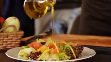 Cook yeşil salata yaprakları ve mango dilimleri ile dilimlenmiş ince dilimlenmiş hafif tuzlu somon bir tabak üzerine zeytinyağı ve balsamik sos serpiştirir