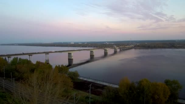 Flygbild över en lång bro över en bred flod, aktiv trafik på bron. bron reflekteras i vattnet. 4K. Kopiera utrymme — Stockvideo