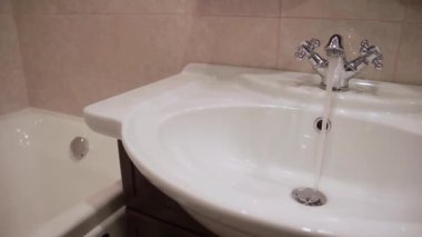 Lavabodaki musluktan su akıyor. Yakın plan..