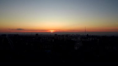Kırmızı-turuncu gün batımında şehir manzarası. Ev evleri. Tv kulesi..