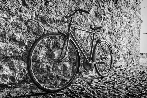 Bicicleta velha em um beco ao lado de uma parede de pedra — Fotografia de Stock