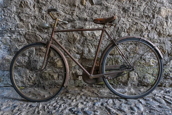 Bicicleta velha em um beco ao lado de uma parede de pedra — Fotografia de Stock