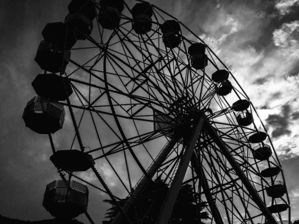 monochrome photo of observation wheel on cloudy sky background