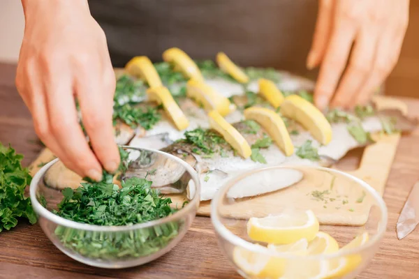 Kvinnliga Händer Förbereda Fisk Öring Med Citroner Och Grönska Träbord — Stockfoto