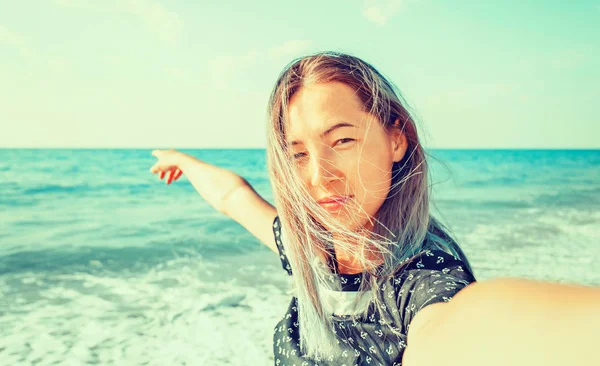 Улыбающаяся Молодая Женщина Смотрящая Камеру Пляже Указывая Море Точка Зрения — стоковое фото