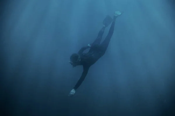ウェット スーツや青の深い海で水中ダイビング足ひれで身に着けているスポーティな若い男フリーダイバー — ストック写真