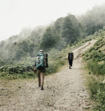 Sisli havalarda, dikiz dağlarda yolda yürüyen sırt çantası ve trekking Polonyalılar ile iki tanınmaz yürüyüşçü.