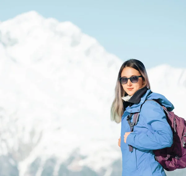 Mochilero mujer de pie en el fondo de las montañas nevadas . —  Fotos de Stock