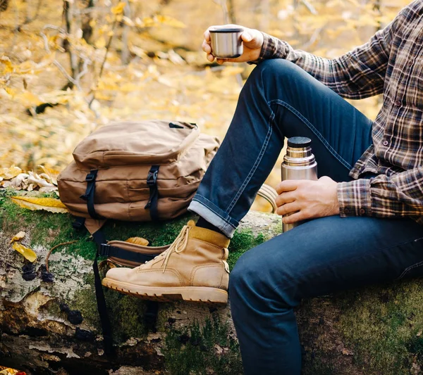 L'uomo poggia su tronco d'albero caduto con thermos . — Foto Stock