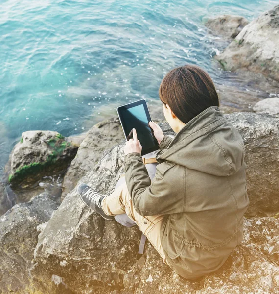 Dijital tablet ile kıyısında oturan genç kadın. — Stok fotoğraf