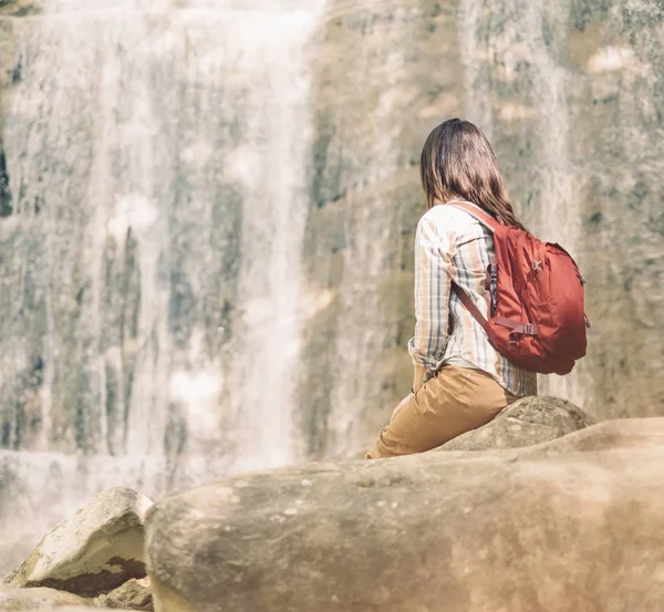 Backpacker kobieta patrząc na wodospad w słoneczny dzień. — Zdjęcie stockowe