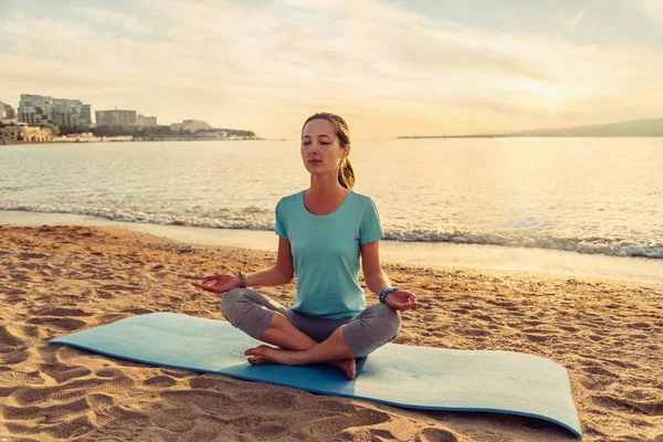 Vrouw mediteren in pose van lotus op strand. — Stockfoto