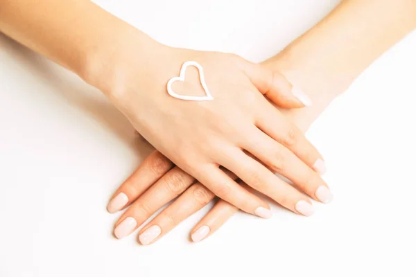 Crema para el cuidado de la piel en forma de corazón en una mano femenina . — Foto de Stock