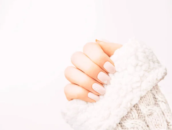 Kobieca ręka z profesjonalnym manicure noszenia w wełnianej swetrze. — Zdjęcie stockowe