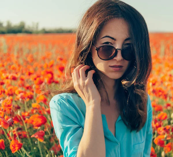 Brunette jonge vrouw in zonnebril in lente bloemen weide. — Stockfoto