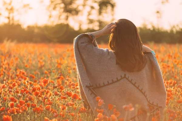 Woman walking in poppies meadow in spring at sunset. — ストック写真