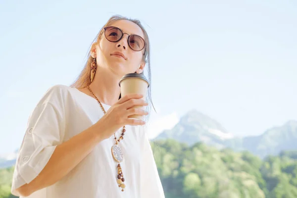Stijlvolle vrouw met kopje koffie op achtergrond van de zomer bergen — Stockfoto