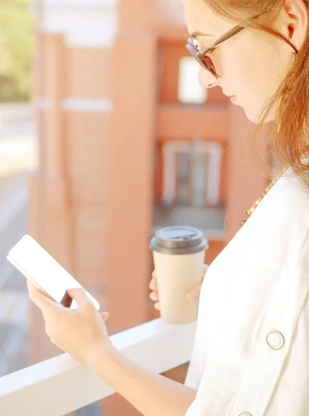 Donna a riposo con tazza di caffè e smartphone sul balcone . — Foto Stock