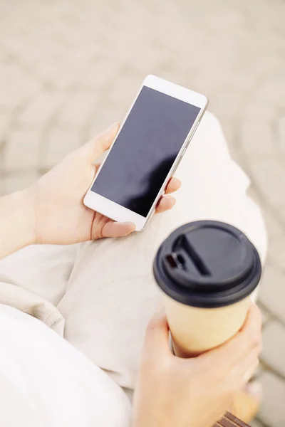 Kahve ve akıllı telefon paket fincan ile tanınmaz kadın. — Stok fotoğraf
