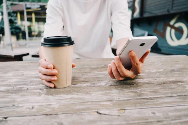 Bir fincan kahve ve cep telefonuyla tahta masada oturan bir kadın! — Stok fotoğraf