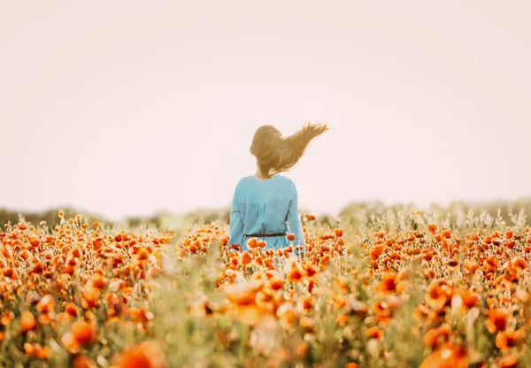 Mujer morena con el pelo de volar de pie en el prado de flores . —  Fotos de Stock