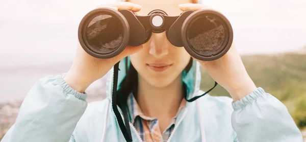 Donna sorridente che guarda con binocolo all'aperto, vista frontale . — Foto Stock