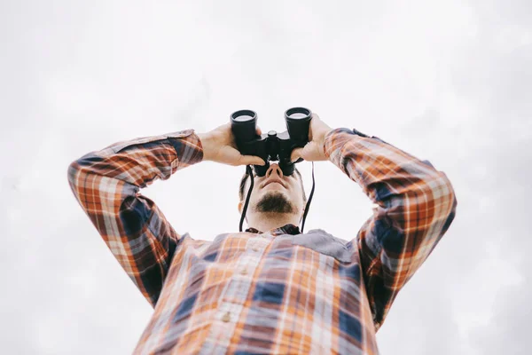 Bottom view of traveler young man watching with binoculars. — Stock Photo, Image