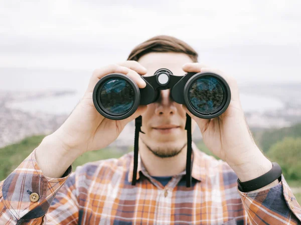 Viajero joven mirando a través de prismáticos al aire libre, frente a la competencia — Foto de Stock