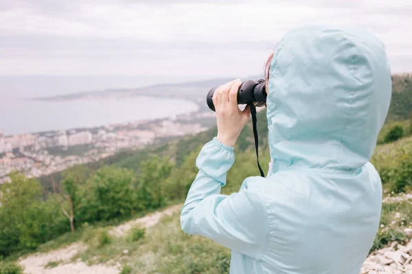 Poutní žena, která hledí dalekohledem na mořské zátoky. — Stock fotografie