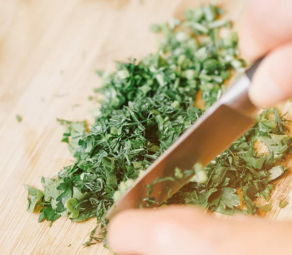 Manos femeninas cortando vegetación sobre tabla de madera, primer plano . —  Fotos de Stock