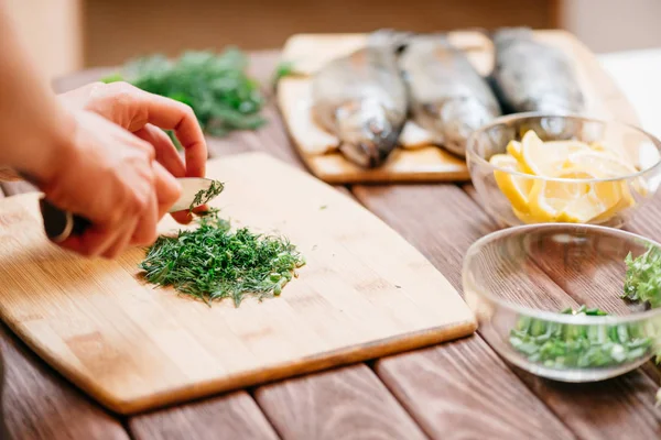 Kvinna skära grönska för fisk skålen på middag. — Stockfoto