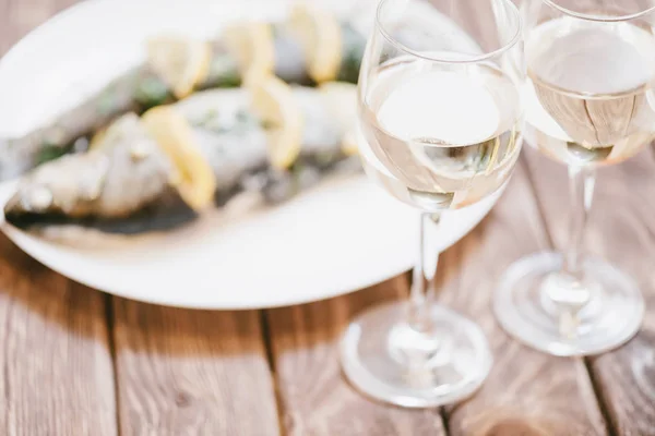 Plato de pescado al horno y dos copas de vino blanco . — Foto de Stock