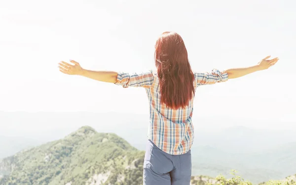 Rear view of woman with raised arms in mountains. — Stock Photo, Image