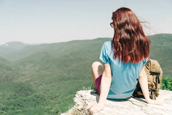 Mochilero mujer descansando en la cima de la roca alta en las montañas de verano —  Fotos de Stock