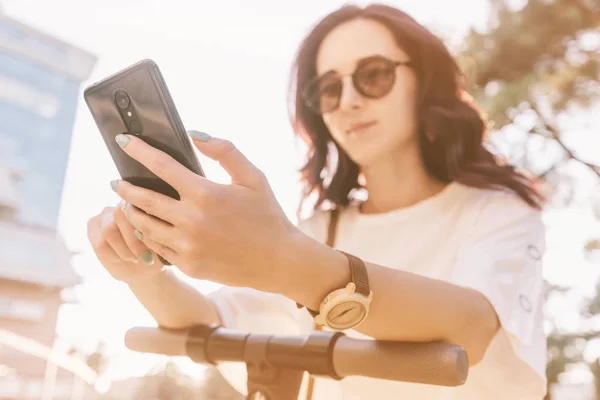 Donna utilizzando smartphone mentre in piedi con scooter in città . — Foto Stock