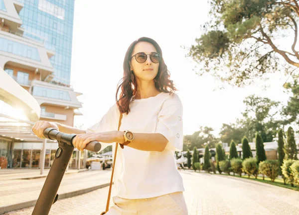 Mujer sonriente con scooter eléctrico en la ciudad . —  Fotos de Stock