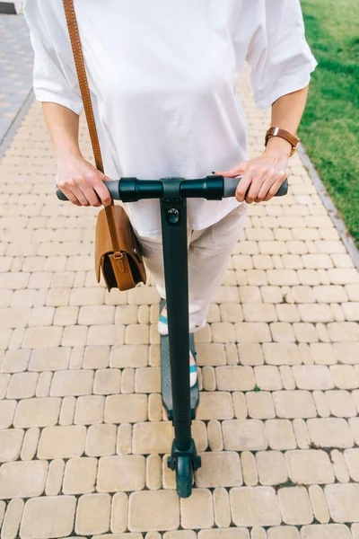 Unrecognizable woman riding an electric scooter in summer park. — Stock Photo, Image