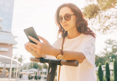 Bir elektrik sc ile ayakta iken akıllı telefon kullanarak modern kadın