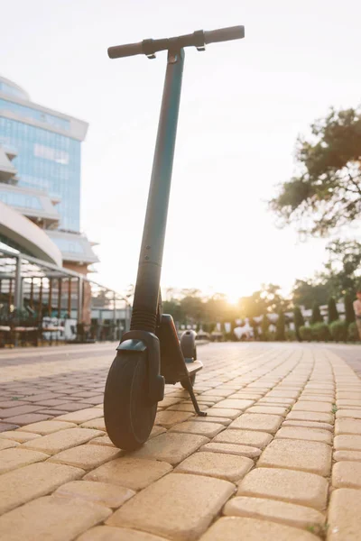 Modern electric scooter in city street at sunset. — Stock Photo, Image