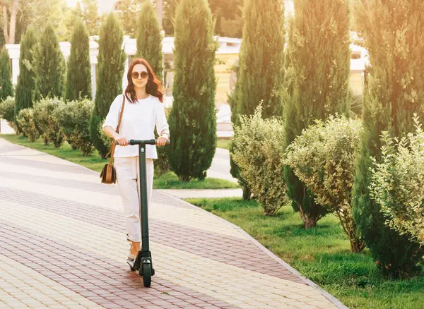 Молодая женщина на электрическом скутере в летнем парке . — стоковое фото