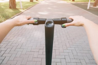 Aktif kadın bir elektrikli scooter sürme, pov.