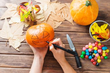 Kadın elleri balkabağı bir yüz çizim ve Hallowee hazırlanıyor