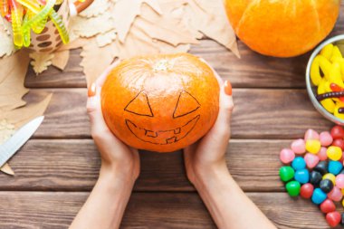 Jack-o-fener çizimi ile balkabağı tutan kadın eller.