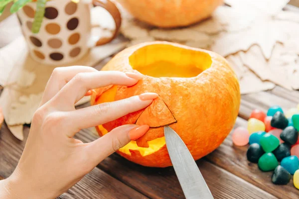 Vrouw handen snijden met mes een pompoen voor Halloween. — Stockfoto